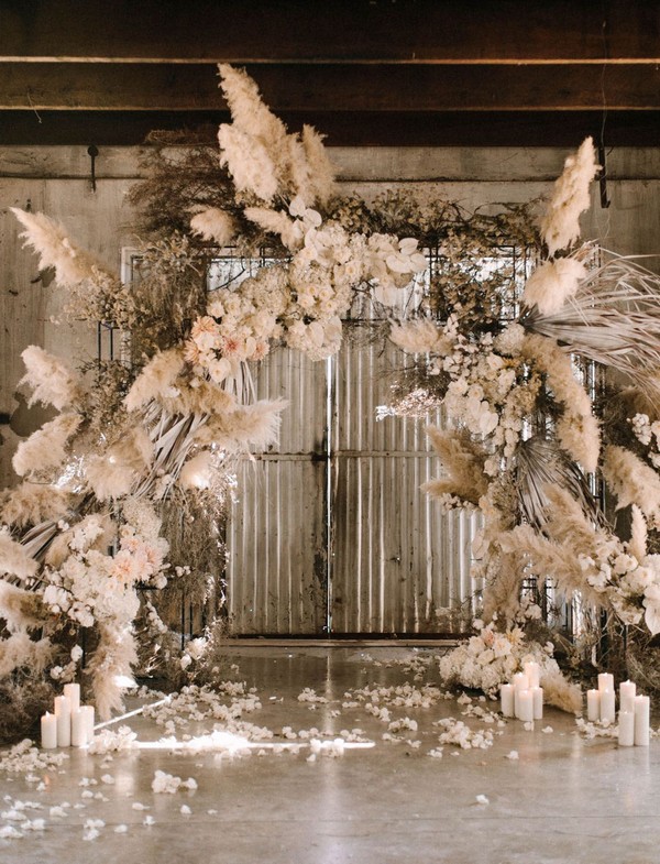 An arch with textured grasses, cotton plants, fragrant roses, hydrangeas, dahlias, and local fynbos, all in white + neutral tones