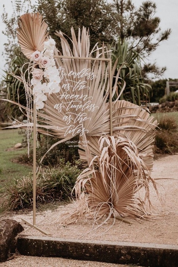 white acrylic welcome sign with pink roses and dried palm leaves